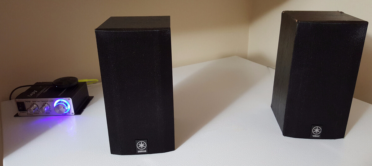 A small black amplifier with two tall black speakers sitting on top of a white surface.